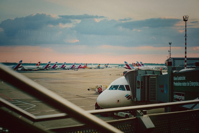 A row of planes on a runway with cloudy sky behind